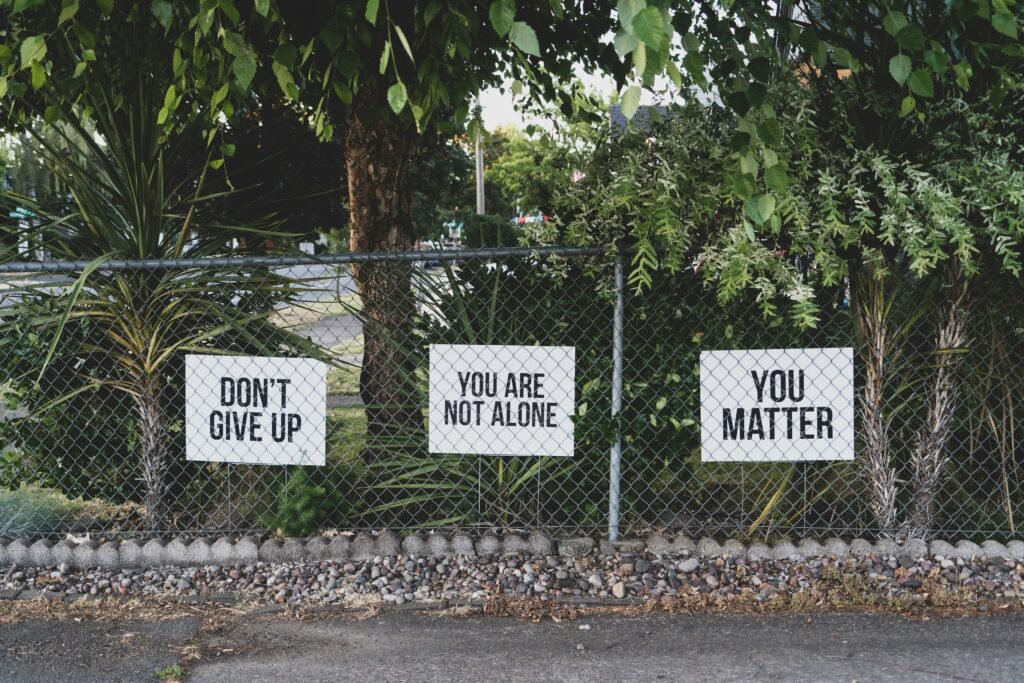 Chain link fence with signs that say "Don't Give Up" "You Are Not Alone" "You Matter"