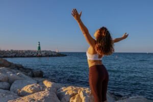 Woman throwing her hands in the air with joy by the ocean