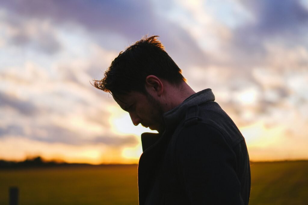 Man with his head down in field