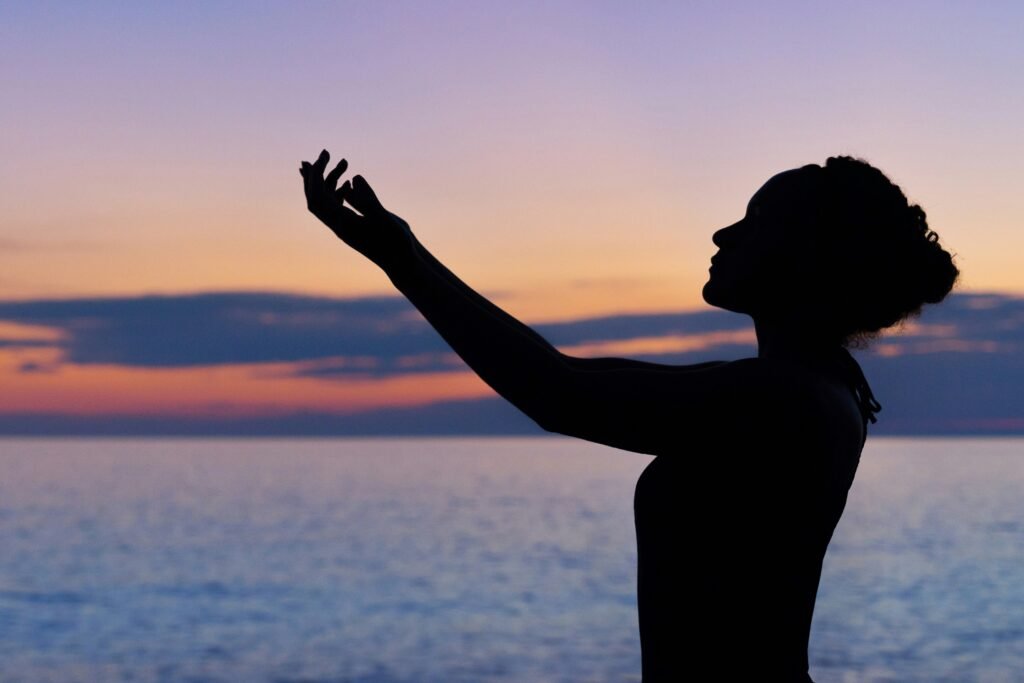 Lady at the beach reaching to the sky